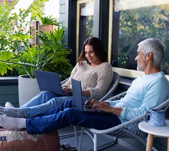 Actor portrayal of a postmenopausal woman on her laptop next to a man conversing with her